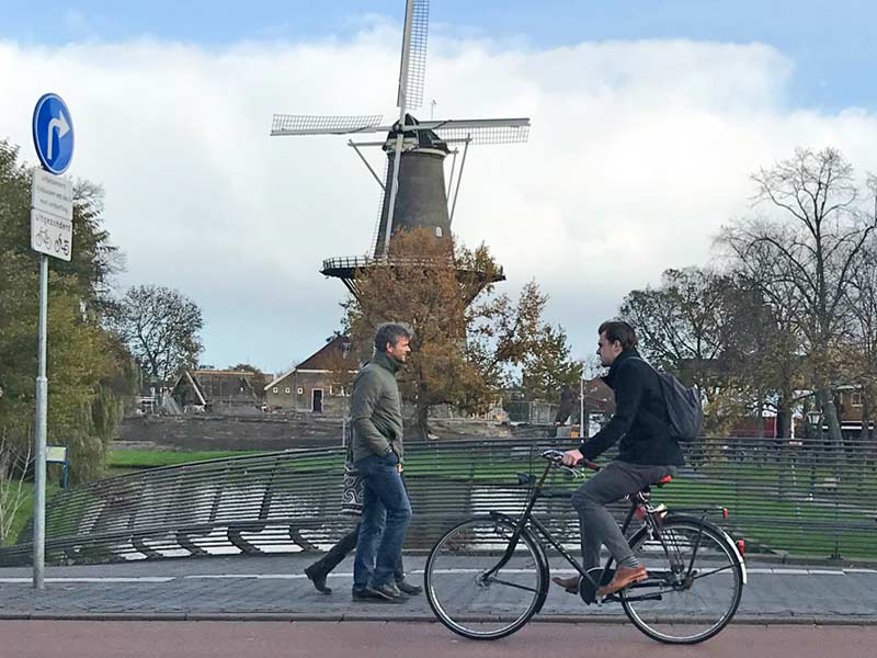 Dutch social integration inburgering - windmill and cyclist in Leiden Netherlands